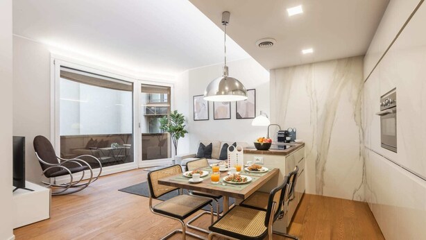 Une cuisine moderne avec un coin repas, comprenant une table en bois, des chaises et un luminaire suspendu.