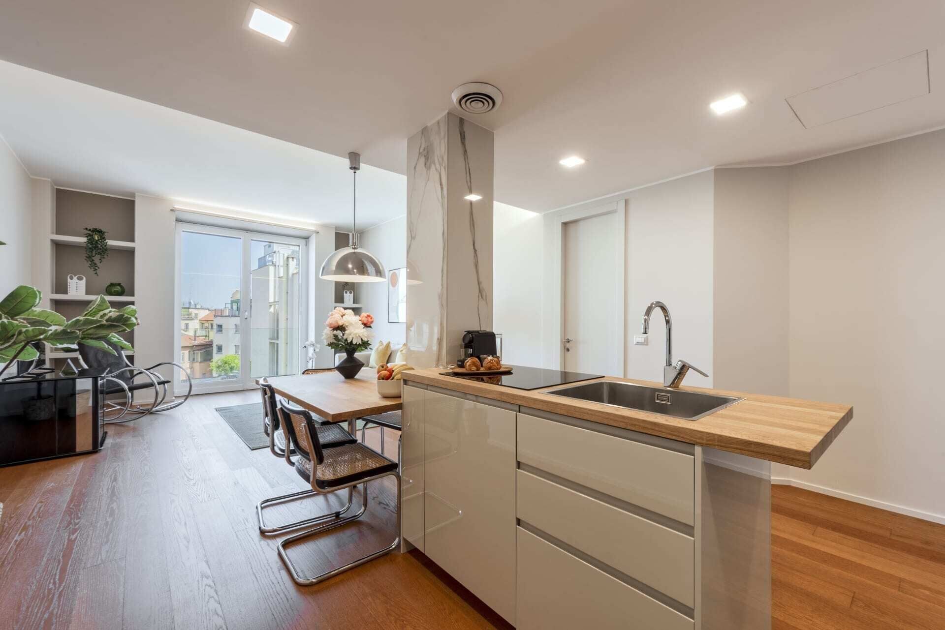 A modern kitchen with a wooden countertop, stainless steel sink, and a dining area with a table and chairs.