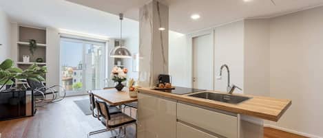 A modern kitchen with a wooden countertop, stainless steel sink, and a dining area with a table and chairs.