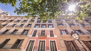 Un immeuble à plusieurs étages doté de balcons, une enseigne indiquant « Suites Center Barcelona » et un lampadaire.