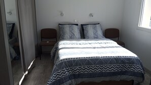 Un dormitorio con una cama, dos mesitas de noche, una silla y un espejo.
