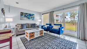 A modern living room with a sofa, blue armchairs, a coffee table, and a patterned rug. - Nautical Watch E-3 (Panama City Beach)