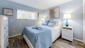 A bedroom with a bed, nightstands, a dresser, and a window with blinds. - Nautical Watch E-3 (Panama City Beach)