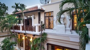 A multi-story building with balconies, large windows, and lush greenery.
