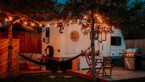 A recreational vehicle (RV) with a cozy outdoor seating area, a grill, and string lights. - RV Glamping w/ Cowboy Tub, Lawn Games & Firepit (Hastings County)