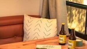 A wooden table with a book and two bottles of beer. - RV Glamping w/ Cowboy Tub, Lawn Games & Firepit (Hastings County)