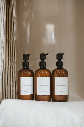 Three bottles of shampoo, conditioner, and body wash on a white surface.
