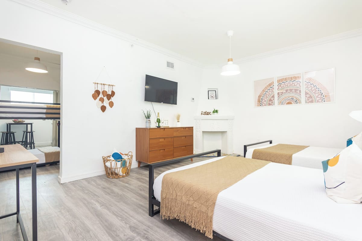 A modern hotel room with a bed, a dresser, a TV, and a dining area.