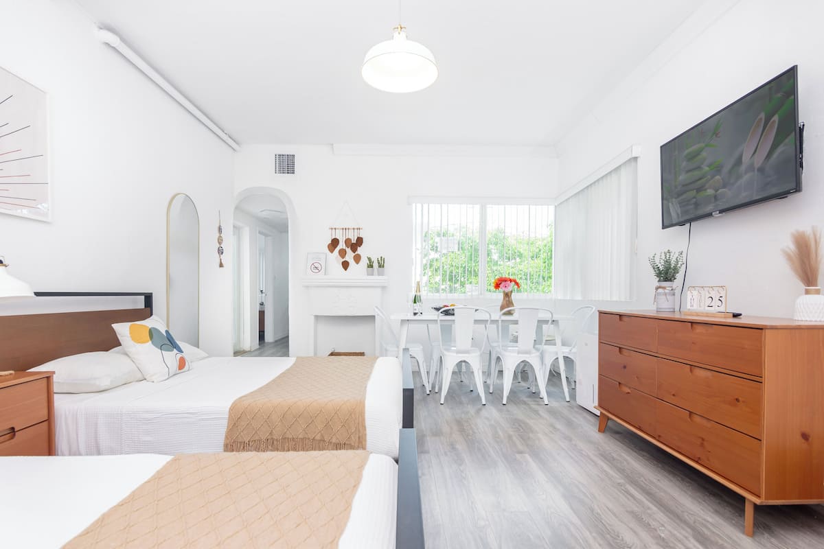 A modern bedroom with a bed, bedside table, dresser, and a TV mounted on the wall.