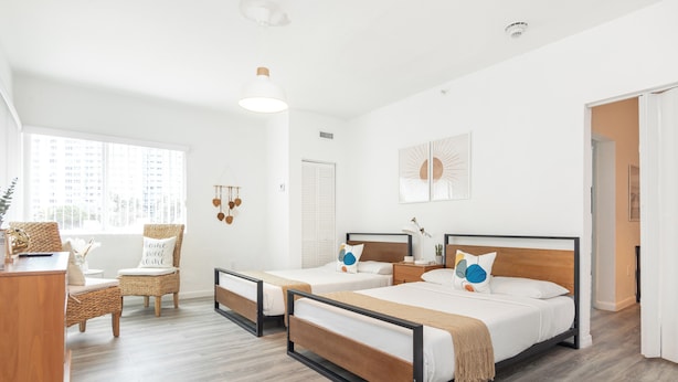 A modern hotel room with two beds, a desk, and a chair. - West Deco Boutique Apartments (Miami Beach)