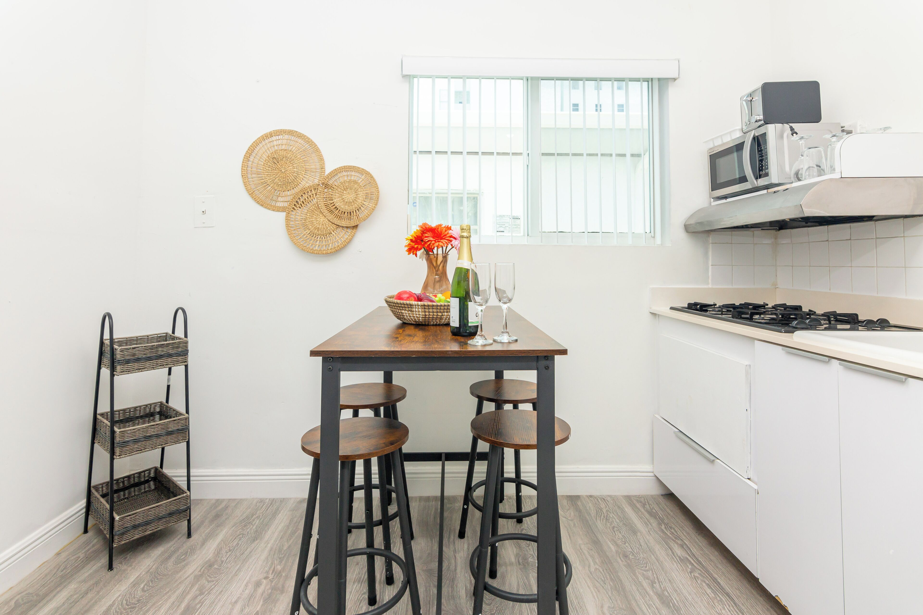 A kitchen with a wooden table, bar stools, a microwave, and a gas stove.
