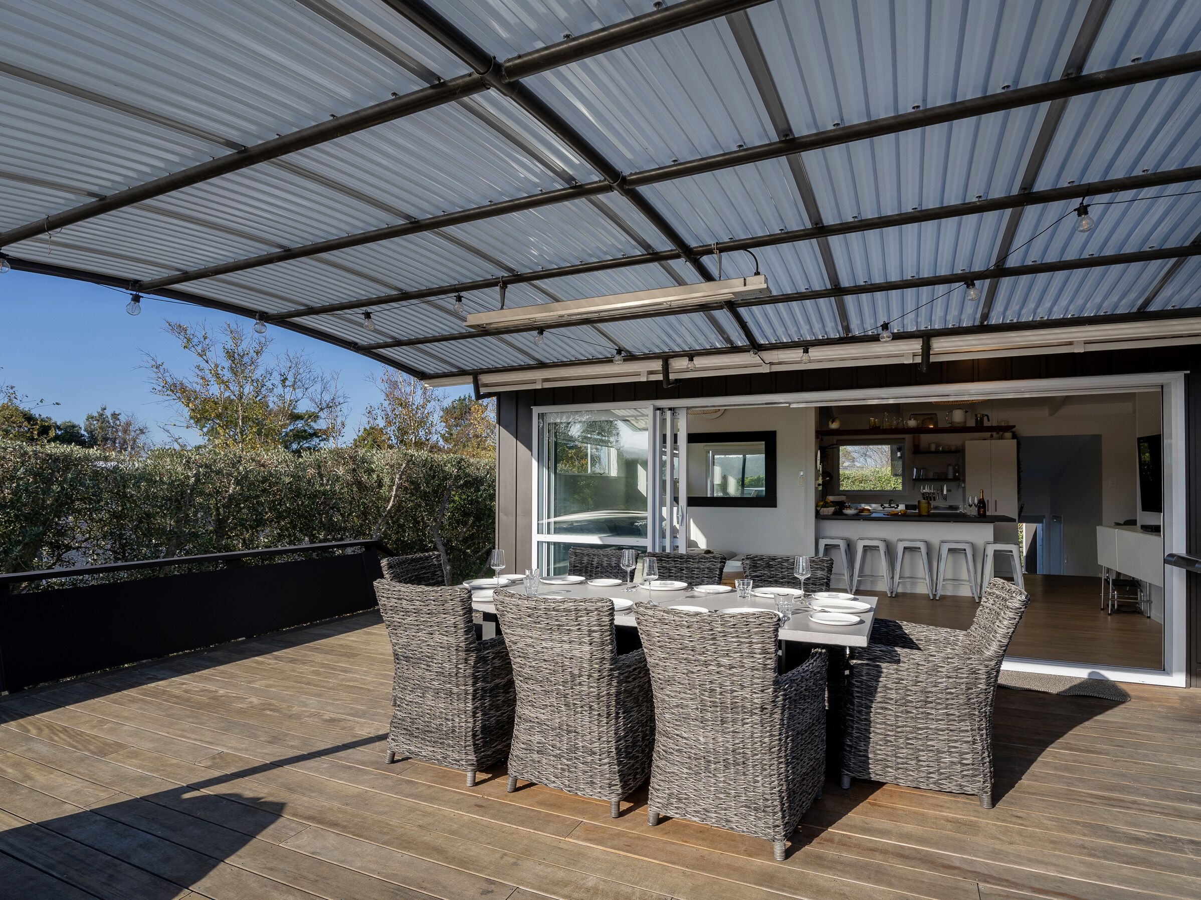 A covered outdoor dining area with wicker furniture and a view into the house.