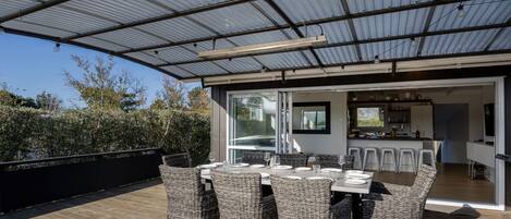 A covered outdoor dining area with wicker furniture and a view into the house.