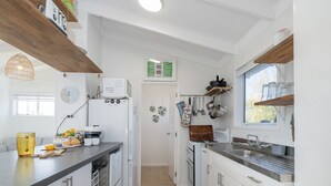 A modern kitchen with white cabinetry, a built-in oven, and a stainless steel sink.