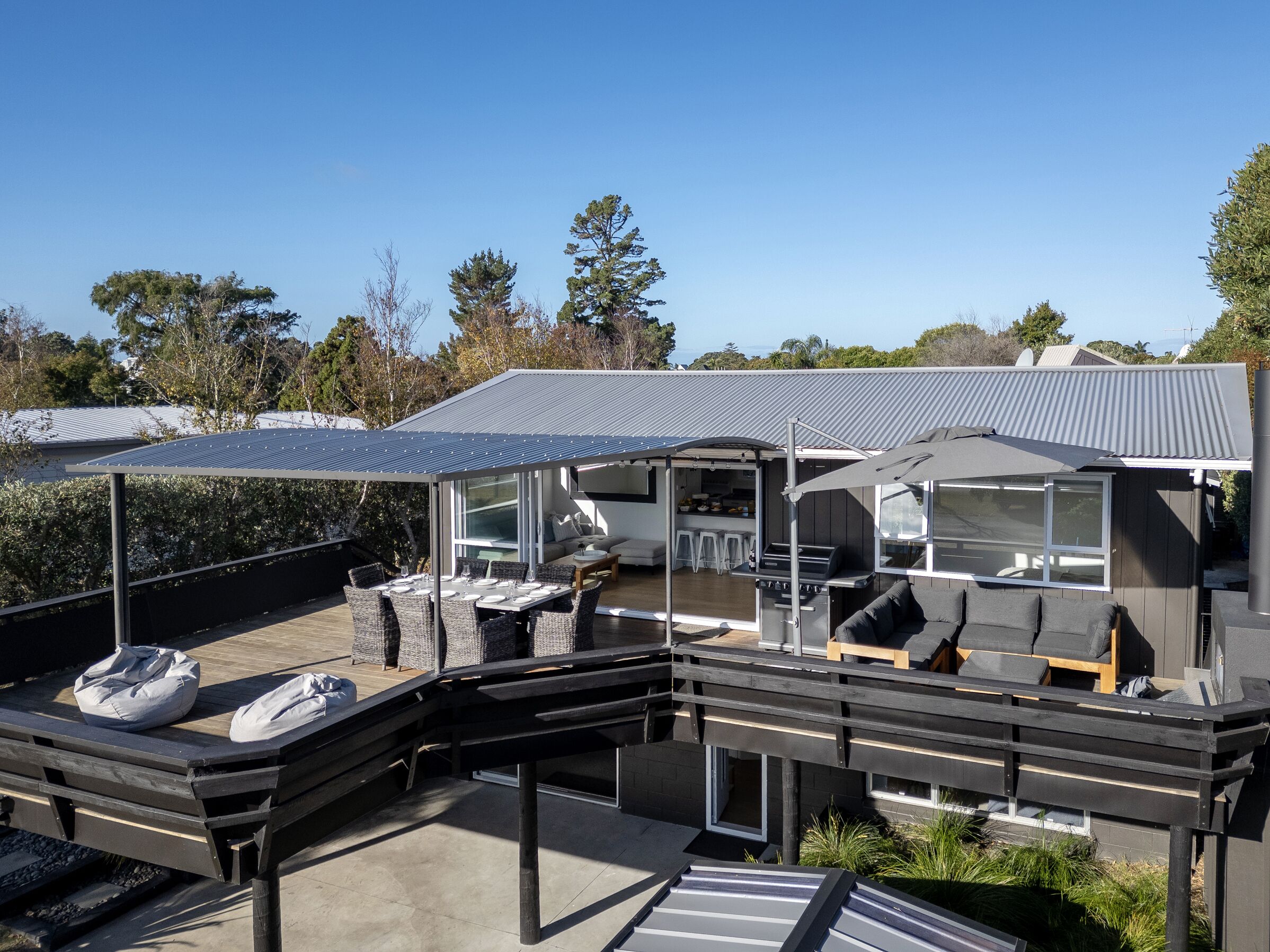 A modern outdoor living space with a dining area, barbecue, and seating.