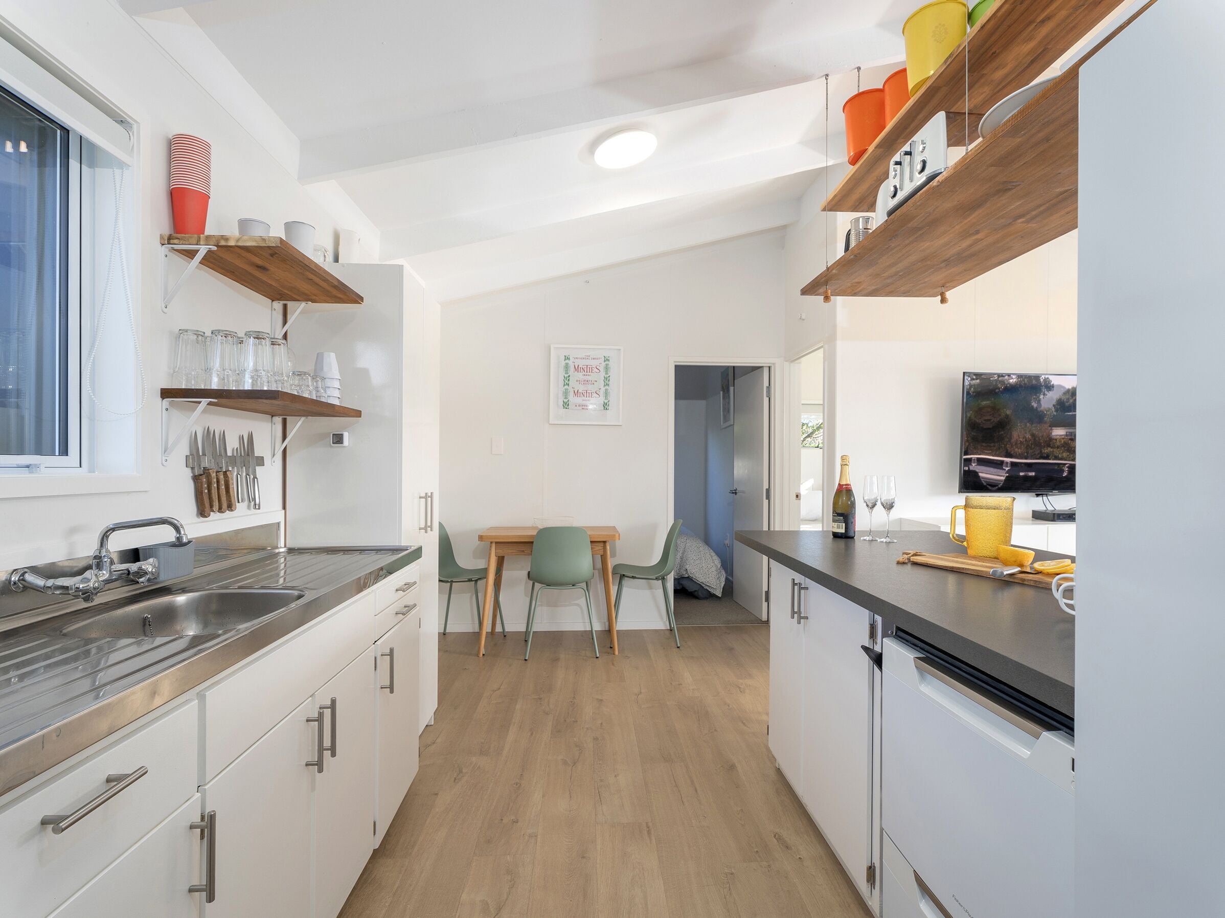 A modern kitchen with white cabinets, a wooden countertop, and a dining area with a table and chairs.
