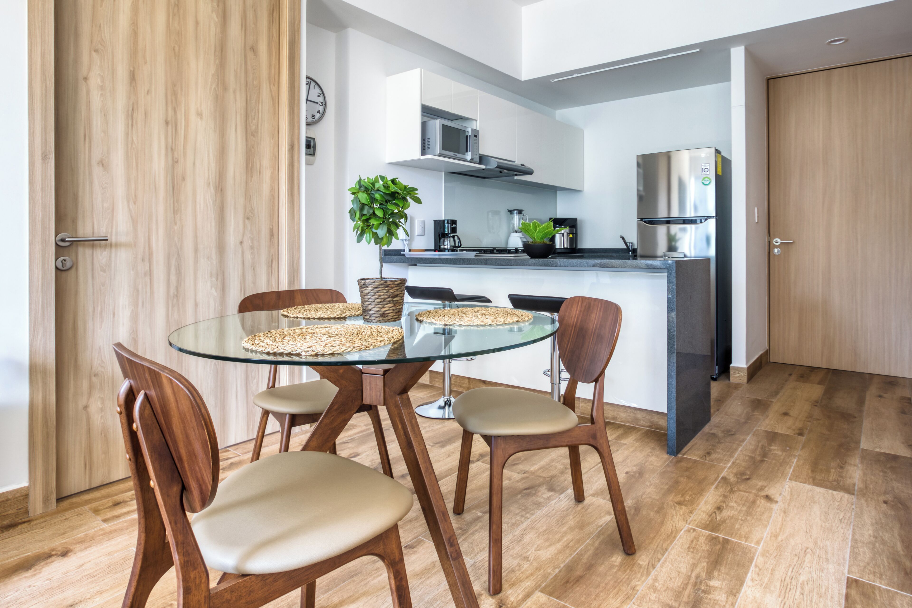 Eine moderne Küche mit einem Glastisch, Holzkreisen, einer Mikrowelle, einem Kühlschrank und einer Kaffeemaschine.