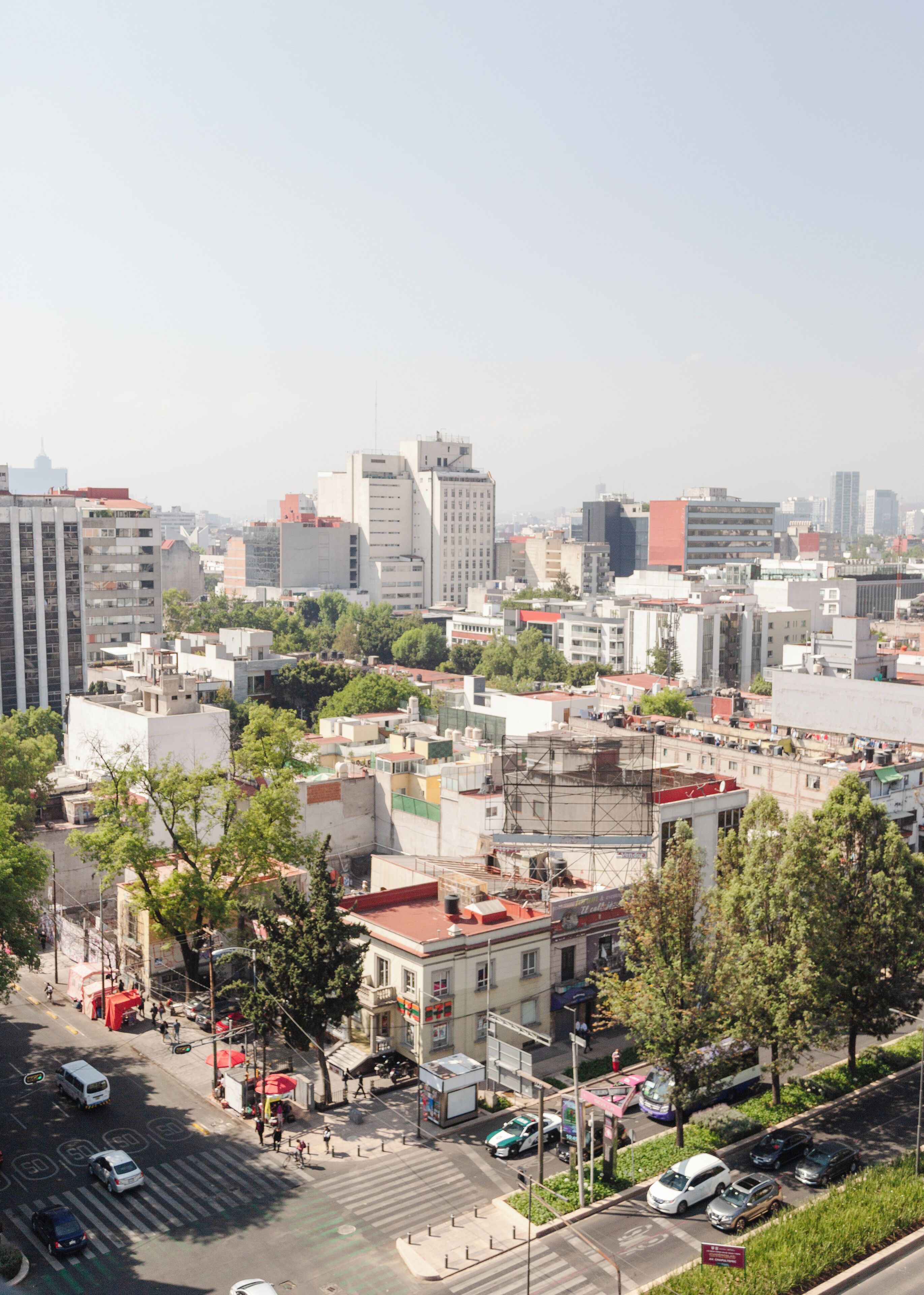 Un paisaje urbano con varios edificios, un paso de peatones y vehículos.