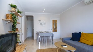 A modern living room with a TV, sofa, and dining area. - SOLIMAR Apartment - Only Families (Cambrils)