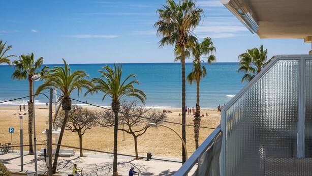 A beach view with palm trees, a clear sky, and a person riding a bicycle. - SOLIMAR Apartment - Only Families (Cambrils)