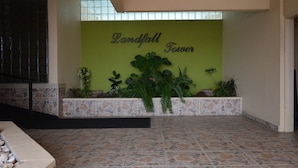 Eine Lobby mit grüner Wand, Steinboden und einem Schild mit der Aufschrift 'Landfall Tower'.