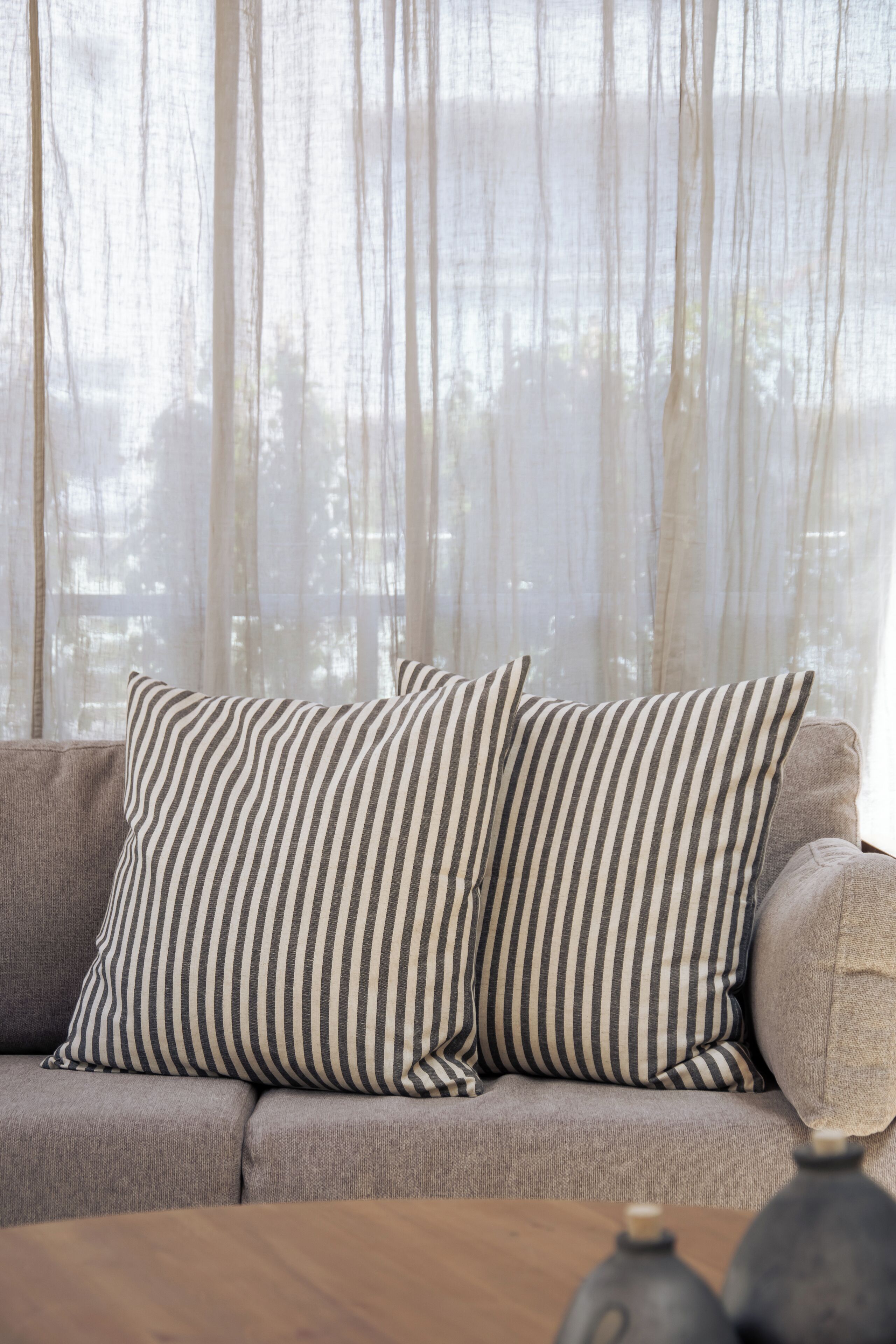 Un sofá con almohadones a rayas y una mesa de madera con jarrones.