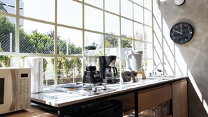 Une cuisine équipée d’un four à micro-ondes, d’une machine à café, d’un mixeur et d’un évier.