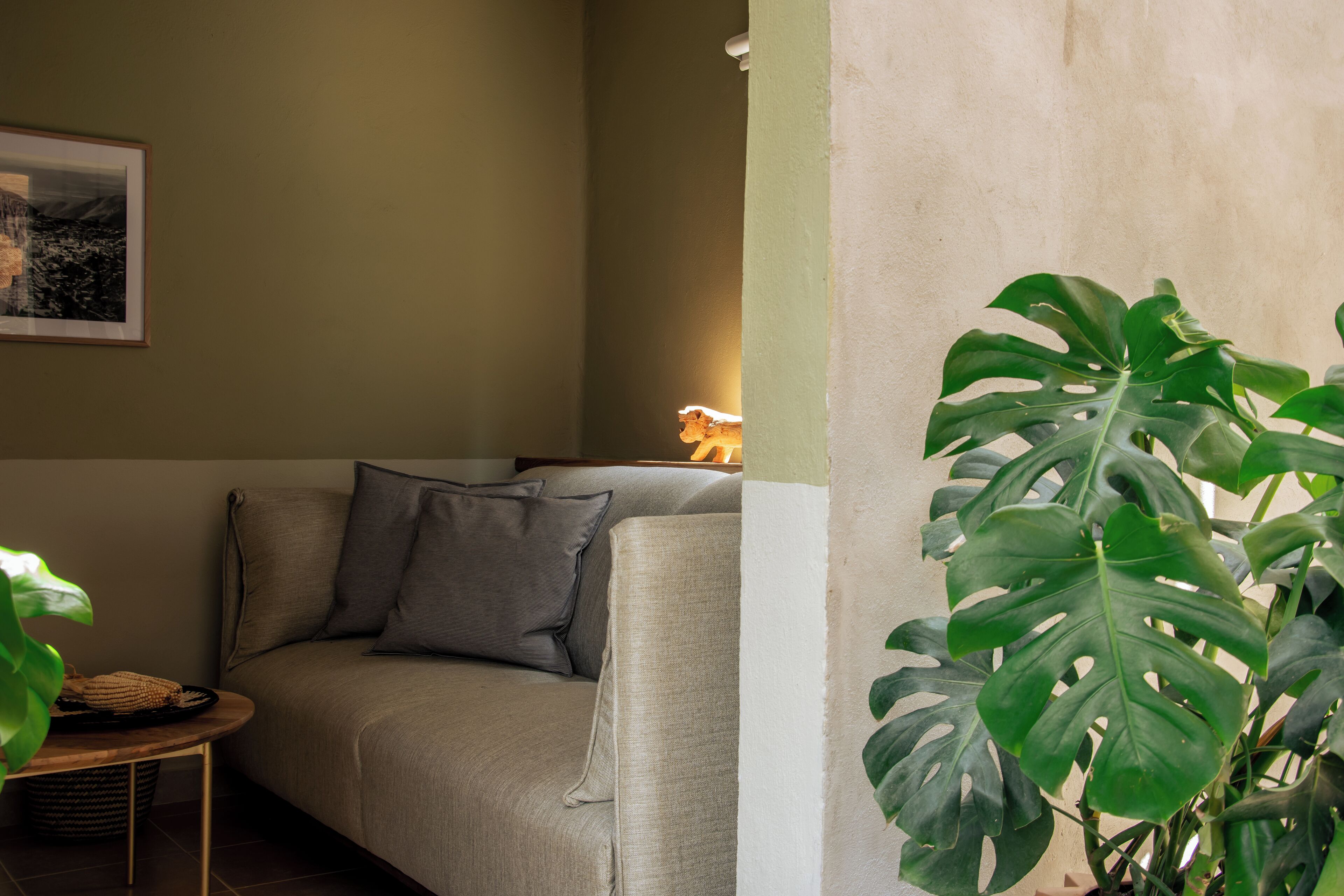 A living room with a sofa, pillows, a small table, and a potted plant.