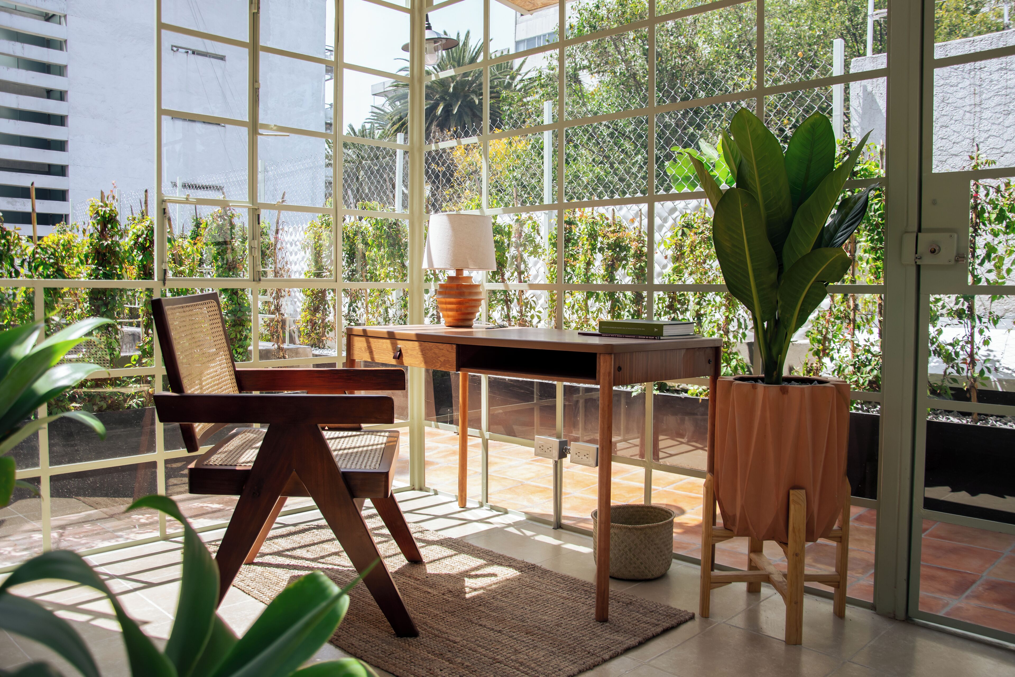 Eine sonnendurchflutete Terrasse mit einem Holztisch, Stühlen und einem Blumentopf.