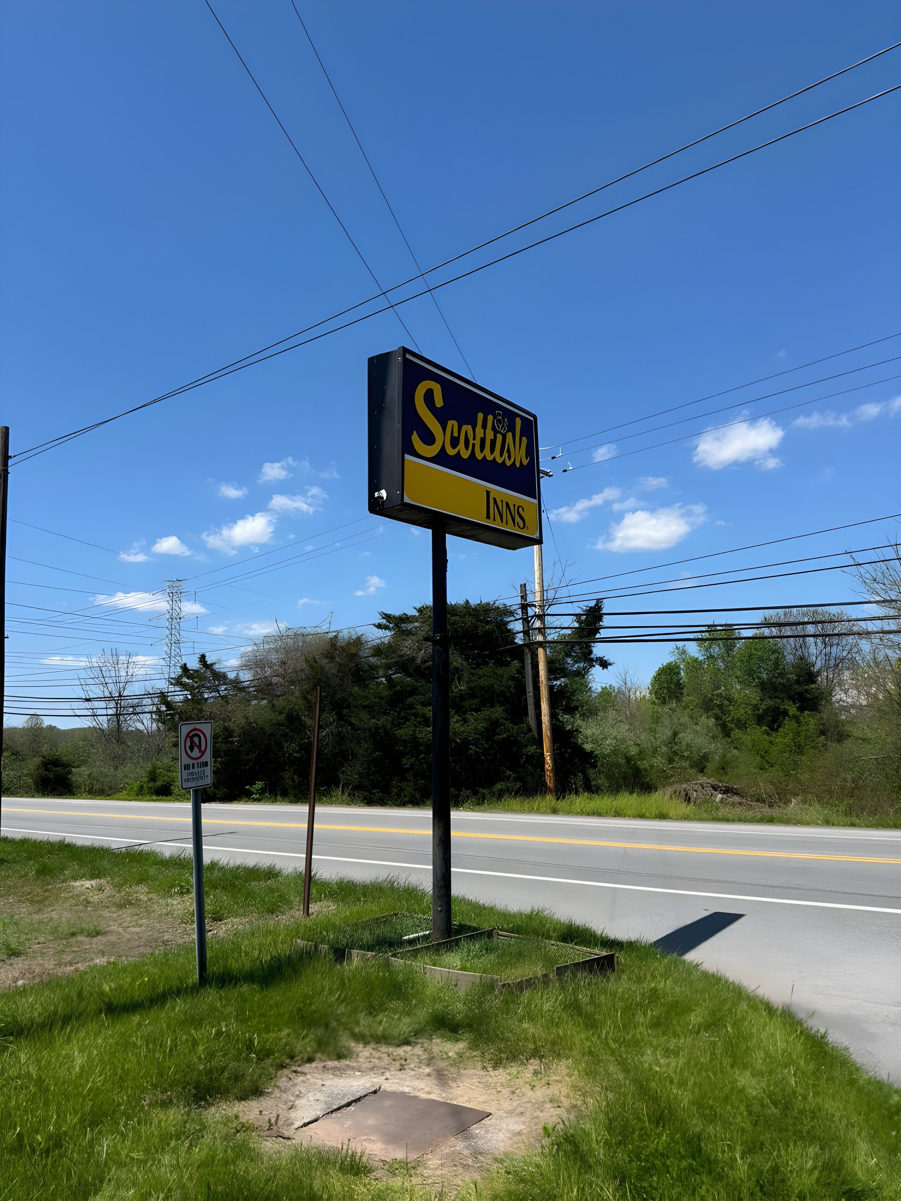 A roadside sign for 'Scottish Inns' with a no U-turn sign nearby.