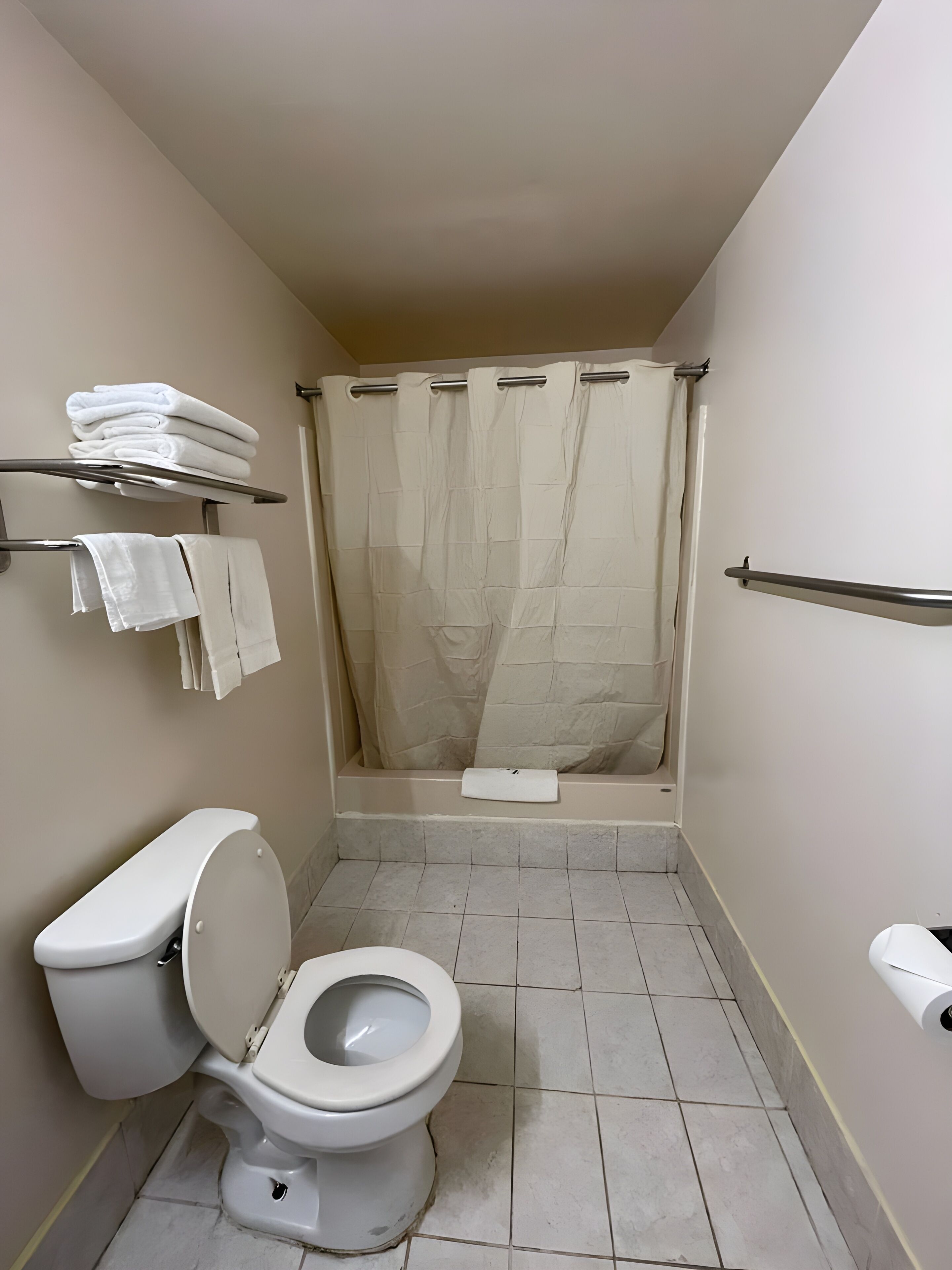 Un bagno piccolo con il water, una tenda della doccia e un porta asciugamani con asciugni piegati.