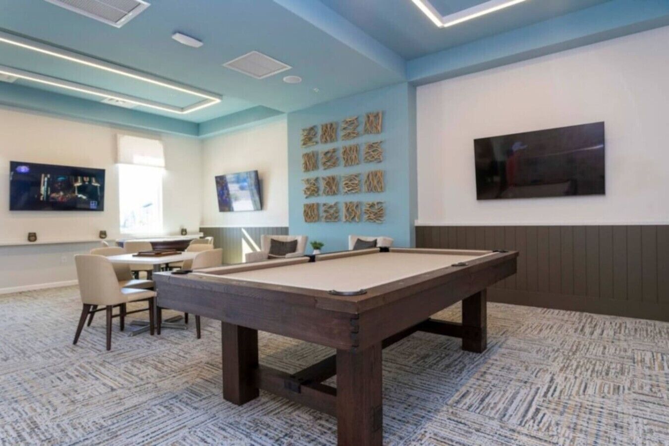 A room with a pool table, chairs, a TV, and artwork on the wall.