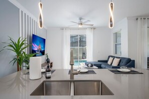 A modern kitchen with a central island, stainless steel sink, and a ceiling fan.