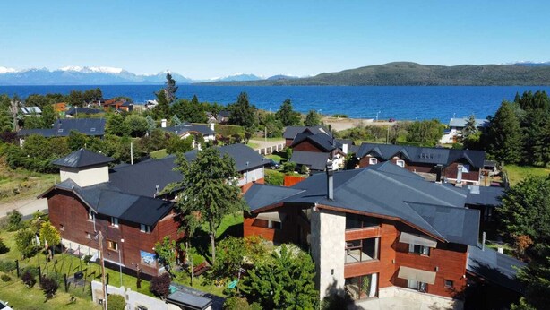 A residential area with modern houses, a clear view of a lake, and mountains in the background.