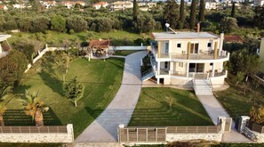 A multi-story house with a central courtyard, surrounded by a well-maintained lawn and trees. - Villa Eva in Eretria Greece , the ideal place for your vacations (Eretria)