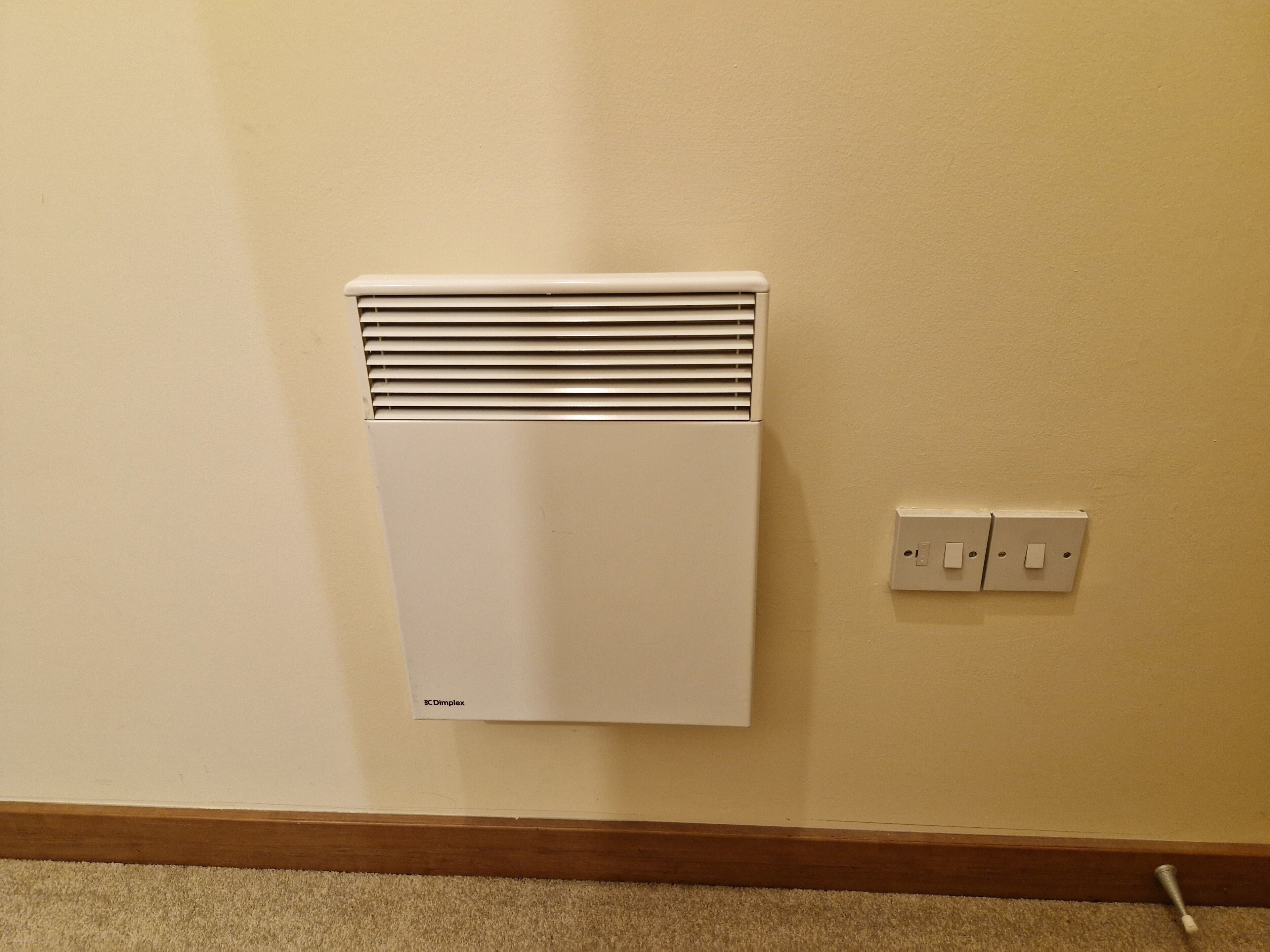 Un radiateur blanc fixé au mur, avec un panneau de commande situé à droite.