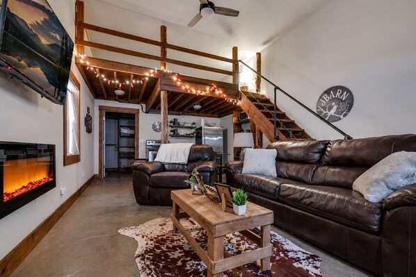 A living room with a fireplace, leather couches, a wooden coffee table, and a staircase.