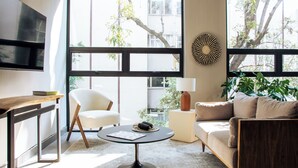 Een moderne woonkamer met een bank, fauteuil, salontafel en een aan de muur bevestigde televisie.