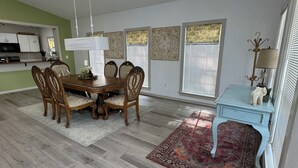 Un coin repas avec une table et des chaises en bois, une petite table d’appoint bleue et un tapis à motifs.