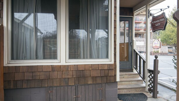A hotel entrance with a wooden facade, large windows with curtains, a visible staircase, and a sign for 'Yonahassee Suite'. - Small Private suite with Electric Fireplace and Pet Friendly (Blowing Rock)