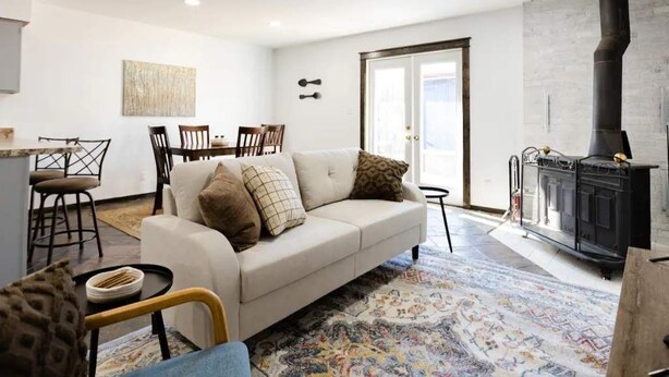 Uma sala de estar com sofá, cadeiras, mesa de jantar e lareira.