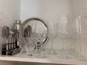 Eine Auswahl an klarem Glas und eine Kaffeemaschine auf einem Regal.