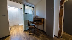 Een kamer met een houten vloer, een bureau met stoel en een spiegel aan de muur.