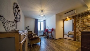 Een ruime woonkamer met houten vloer, een eettafel met stoelen, een bank en een decoratief wandobject.