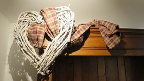 A heart-shaped wreath made of twigs and plaid fabric, placed on a wooden surface.