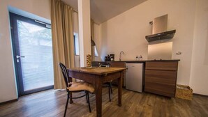 A compact kitchen with a dining table and chairs, a small refrigerator, and a built-in oven.
