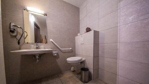 A bathroom with a sink, mirror, toilet, and hand dryer.