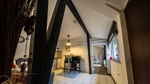 A narrow hallway with a tiled floor leading to a kitchen area with a table and chairs. - Saint Martin Guesthouse LE Vauban (NEUF BRISACH)