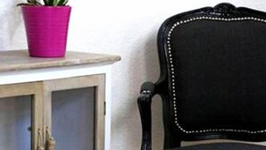 Een houten kast met glazen deuren en een zwarte stoel met witte stiksels.