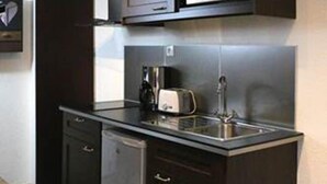 A compact kitchen with dark cabinetry, a built-in microwave, a toaster, and a sink. - Briancon Guesthouse LE Vauban (NEUF BRISACH)